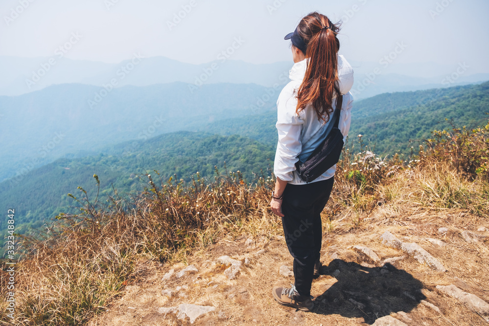 A woman hiking and standing on the top of mountains looking at a beautiful view