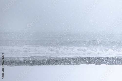 Snowing on the beach with a rough sea in the background.Snowy conitions by the sea in TAdzikidziri beach, CAUCASUS.Global warming warnings and change of weather.