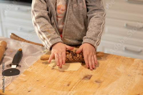 Child hands flattening some pizza dough with a rolling pin