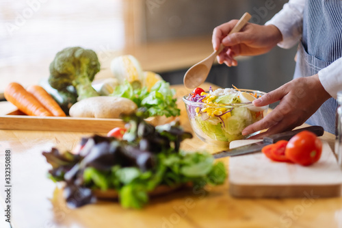 фотографія Closeup image of a female chef cooking and holding a bowl of fresh mixed vegetab