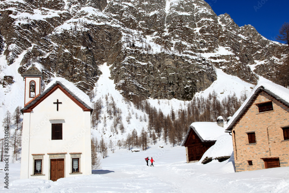 Devero Park ( Verbano-Cusio-Ossola ), Italy - January 15, 2017: The church in Crampiolo village at Alpe Devero Park, Ossola Valley, VCO, Piedmont, Italy Devero Park ( Verbano-Cusio-Ossola ), Italy - January 15, 2017: The church in Crampiolo village at Alpe Devero Park, Ossola Valley, VCO, Piedmont, Italy