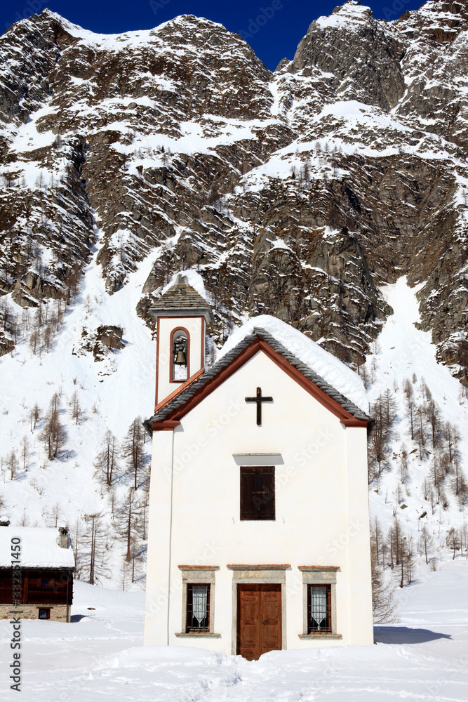 Devero Park ( Verbano-Cusio-Ossola ), Italy - January 15, 2017: The church in Crampiolo village at Alpe Devero Park, Ossola Valley, VCO, Piedmont, Italy Devero Park ( Verbano-Cusio-Ossola ), Italy - January 15, 2017: The church in Crampiolo village at Alpe Devero Park, Ossola Valley, VCO, Piedmont, Italy