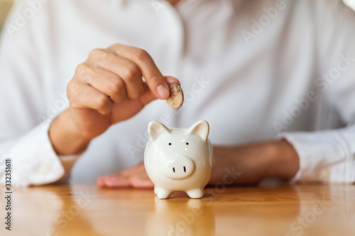 Fotografija A woman putting coins into piggy bank for saving money concept