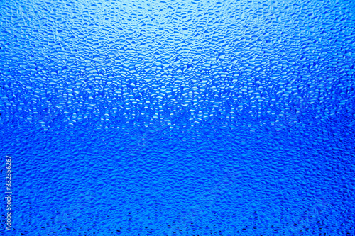Blue translucent relief glass, gradient background. Water drops on blue background