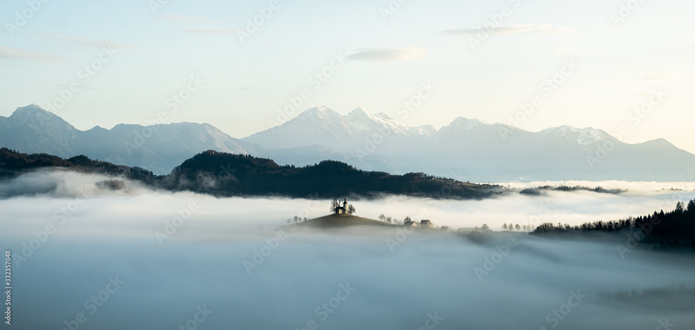Sveti Tomaz church near skofja loka in Slovenia with low fog at sunrise