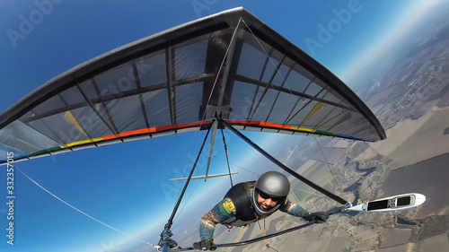 Hang glider pilot with his colorful wing flies alone far from other people.