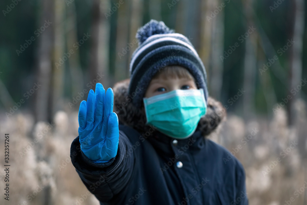 Child in protective sterile medical mask on her face looking at camera outdoors Child in protective sterile medical mask on her face looking at camera outdoors