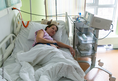 Pregnant woman feels hard contraction in a hospital labor delivery room. Concept photo of pregnancy, pregnant woman, newborn and baby.