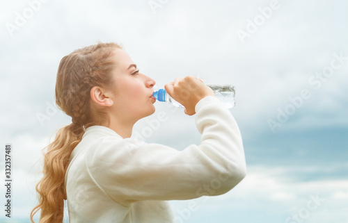 A young woman drinks water from a bottle.