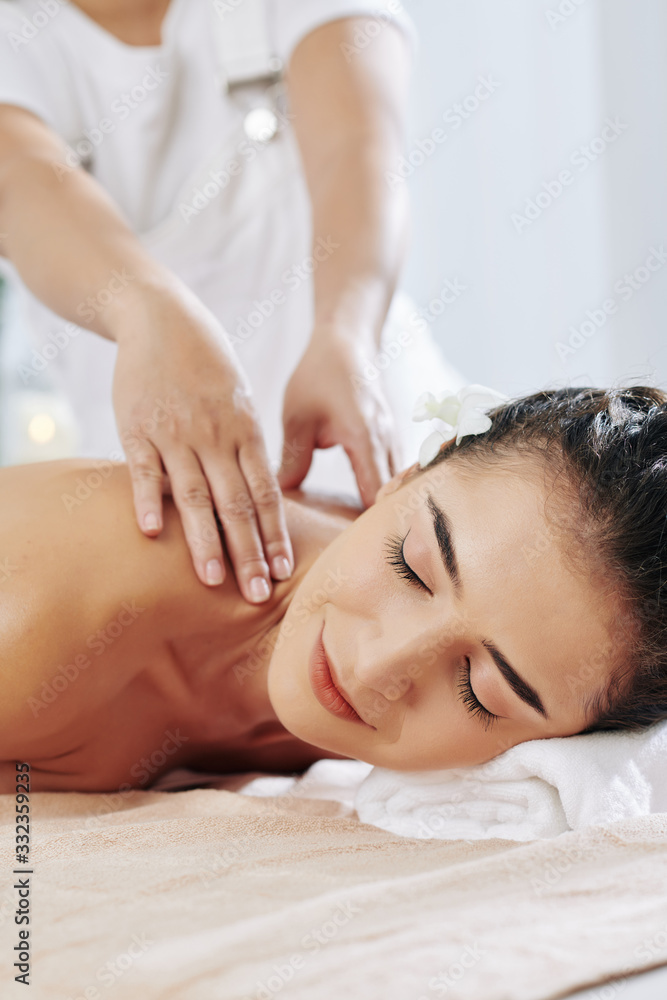 Smiling pretty young woman enjoying shoulder massage in spa salon Smiling pretty young woman enjoying shoulder massage in spa salon