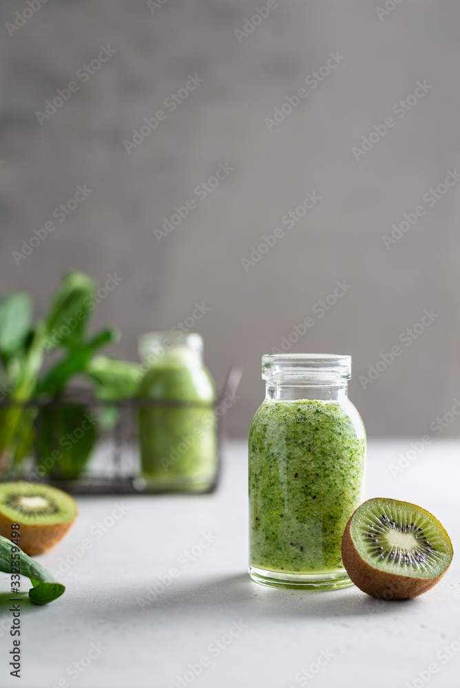 Fresh organic green smoothie with spinach, apple and kiwi in a glass bottle on light background. Detox menu, dieting, healthy food. Side view, copy space Fresh organic green smoothie with spinach, apple and kiwi in a glass bottle on light background. Detox menu, dieting, healthy food. Side view, copy space