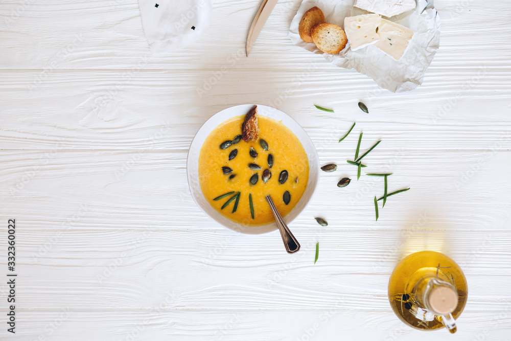 Pumpkin cream soup with cheese and onions on a white board. Still life flat lay Pumpkin cream soup with cheese and onions on a white board. Still life flat lay