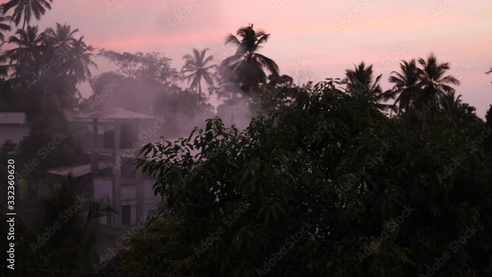 Smoke from a fire rises over a village in a tropical area. Bonfire. Burning garbage. Smoke from a fire rises over a village in a tropical area. Bonfire. Burning garbage.