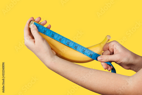 Measuring the size of a banana as a symbol of the male penis on yellow background. Big dick length. Strong erection and impotence problem. photo