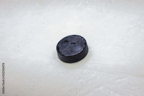 Black old ice hockey puck on ice rink.