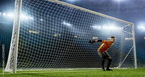Goalkeeper is trying to save from a goal on an empty soccer stadium. No spectators on the tribunes. Stadium is made in 3d. © haizon