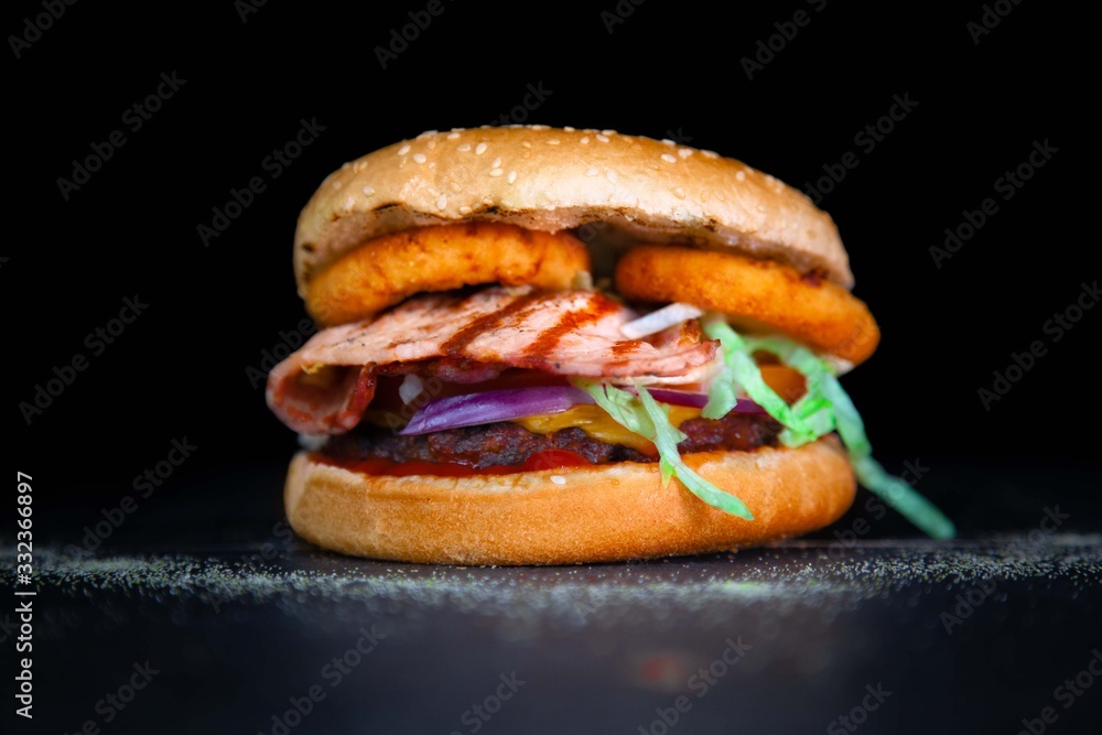 Tasty cheese burger with grilled bacon and onion rings Tasty cheese burger with grilled bacon and onion rings
