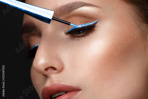 Cuadro en lienzo Beautiful girl with sexy lips and classic makeup with cosmetic blue eyeliner in hand