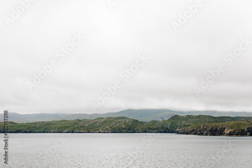 Aview over the scottish coastline from across the ocean with cloudy sky photo