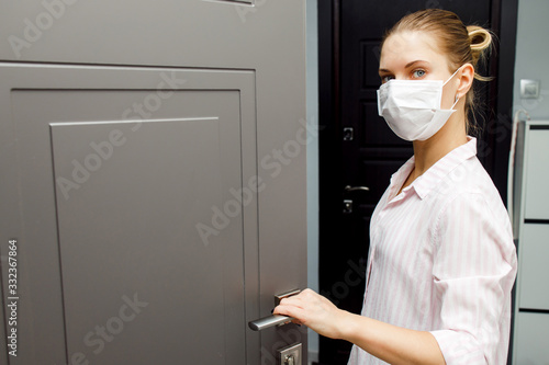 Close-up of young blonde in medical mask opening door