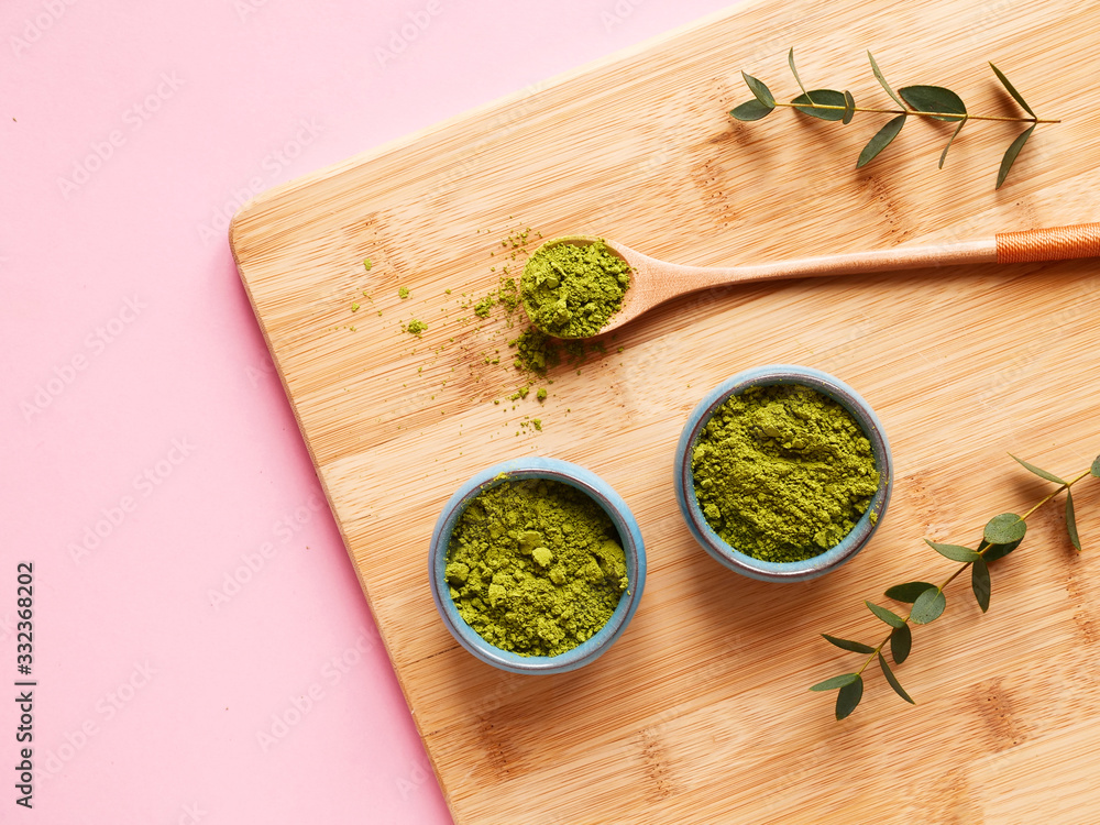 matcha tea on wooden cutting board with spoon and leaf on pink background. Concept healthy drink, detox, close up. matcha tea on wooden cutting board with spoon and leaf on pink background. Concept healthy drink, detox, close up.
