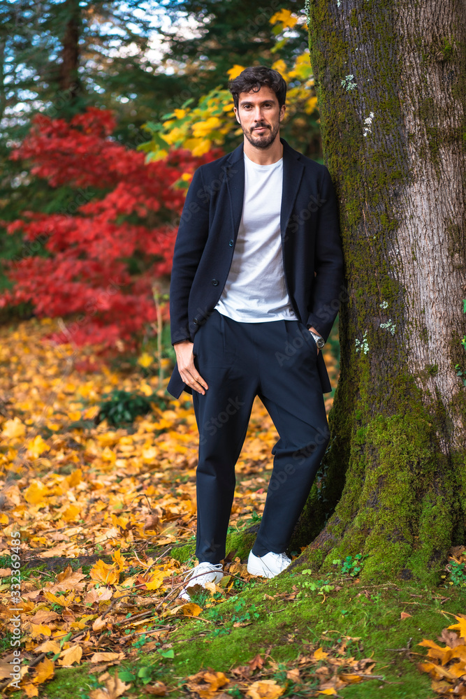 A young entrepreneurial businessman in an autumn session leaning against a tree A young entrepreneurial businessman in an autumn session leaning against a tree