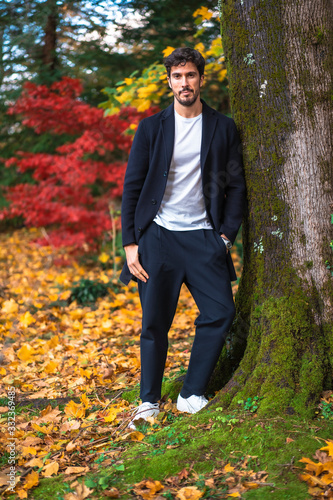 A young entrepreneurial businessman in an autumn session leaning against a tree