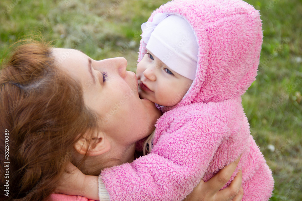 mom sits on the grass in the shade of a blossoming apple tree. plays and hugs his daughters mom sits on the grass in the shade of a blossoming apple tree. plays and hugs his daughters