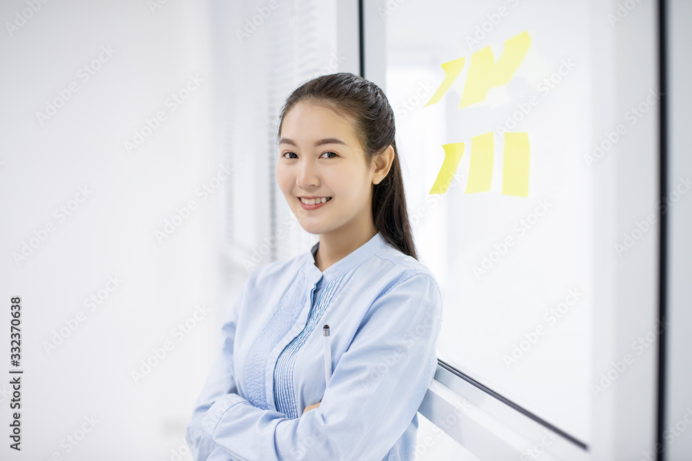 Asian young businesswoman holding and using laptop computer at glass room office with sticky note backside Asian young businesswoman holding and using laptop computer at glass room office with sticky note backside