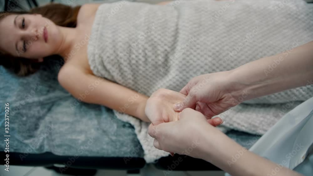 Massage - masseuse is kneading fingers on the palm of a woman on a couch Massage - masseuse is kneading fingers on the palm of a woman on a couch
