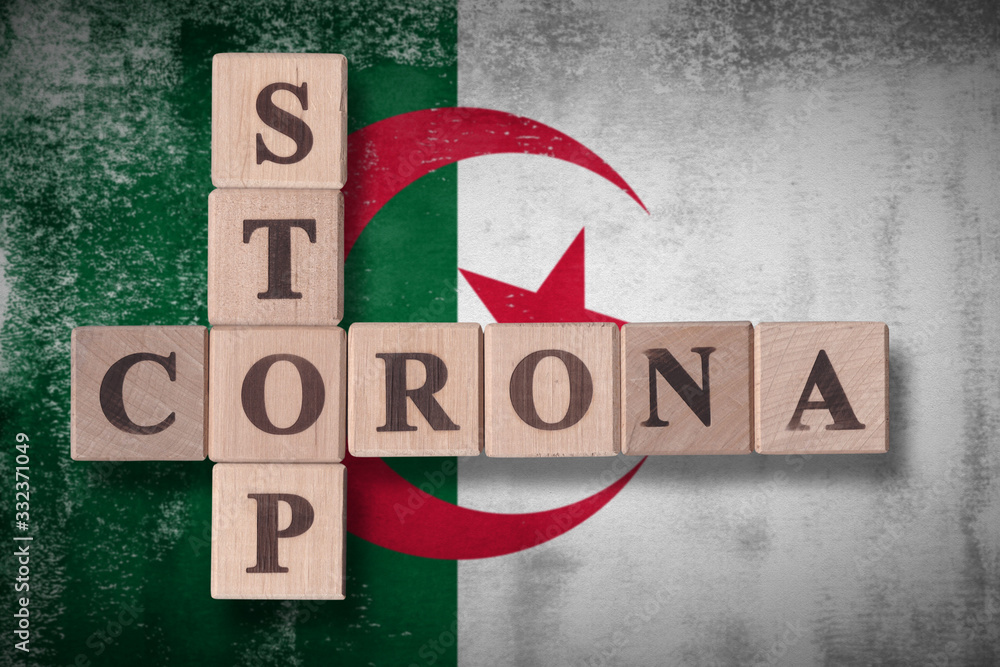 Obraz premium Flag of Algeria with wooden cubes spelling STOP CORONA on it. 2019 - 2020 Novel Coronavirus (2019-nCoV) concept art, for an outbreak occurs in Algeria.