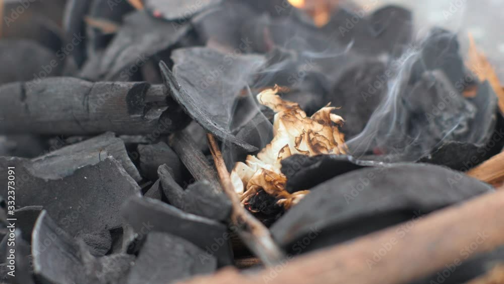Burning paper on charcoal for grilling. Paper burns on smoldered coals. Burning paper on charcoal for grilling. Paper burns on smoldered coals.