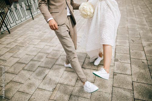 Bride and groom on the street show their shoes. Not classic wedding shoes