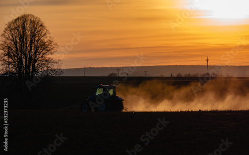 Tractor silhouette in the field on the orange-yellow sunset