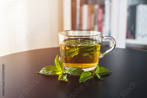 Mint tea on black table. Library in background. Tea time. Yellow tea close up.