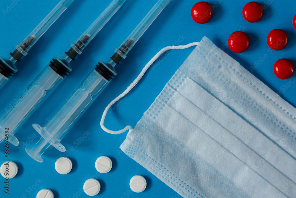 medical mask, syringes and pills, on blue background