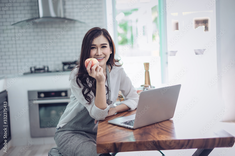 Portrait of beautiful young latin woman talking over the phone while cooking in kitchen