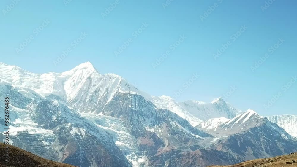 A couple enjoying the view form Ice lake, part of the Annapurna Circuit Trek, Himalayas, Nepal. Annapurna chain in the back, covered with snow. Clear weather, dry grass, snowy peaks. High altitude A couple enjoying the view form Ice lake, part of the Annapurna Circuit Trek, Himalayas, Nepal. Annapurna chain in the back, covered with snow. Clear weather, dry grass, snowy peaks. High altitude