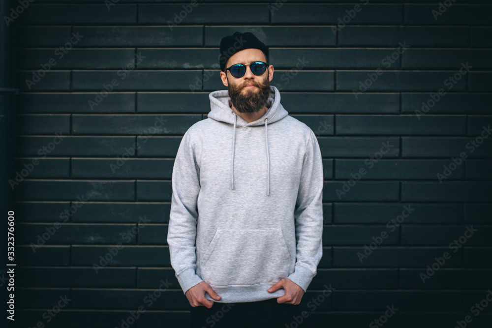 City portrait of handsome hipster guy with beard wearing gray