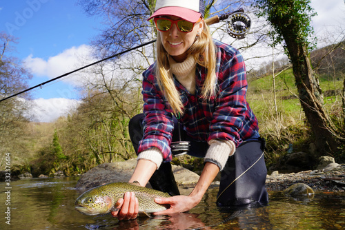woman catching rainbow trout fly in river