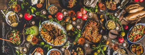 Flat-lay of Turkish traditional foods sush as lamb chops, quince, green beans, vegetable salad, babaganush, rice pilav, pumpkin dessert, lemonade over rustic table, top view, wide composition photo