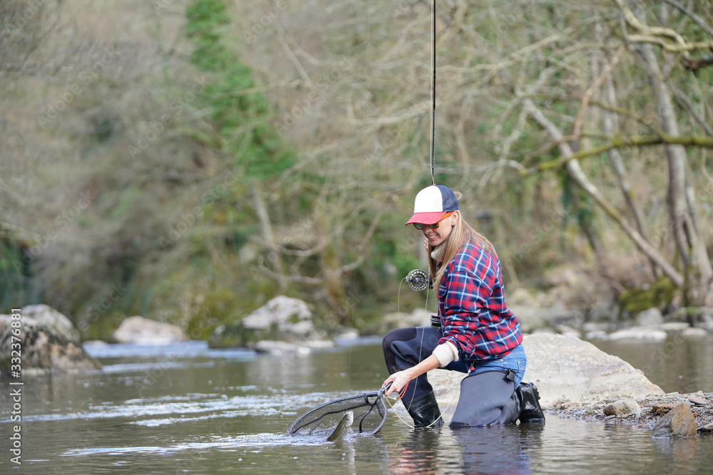 woman catching rainbow trout fly in river woman catching rainbow trout fly in river