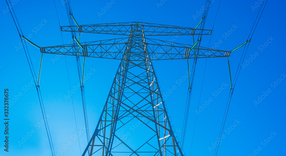 Transmission tower in a blue sky in sunlight in spring