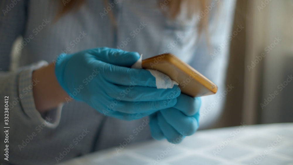 Hands cleaning smartphone with a disinfectant napkin