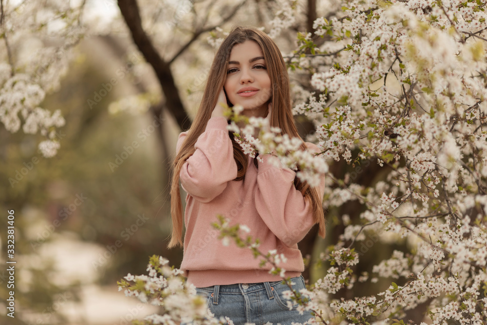 Portrait of pretty young girl in the garden of blossom cherry trees. Spring time
