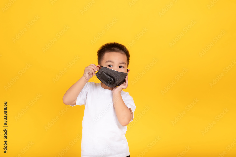 Little asian children boy wearing medical mask protection coronavirus COVID-19 or dust pm2.5 safety healthy self air pollution concept on yellow background, copy space. Little asian children boy wearing medical mask protection coronavirus COVID-19 or dust pm2.5 safety healthy self air pollution concept on yellow background, copy space.