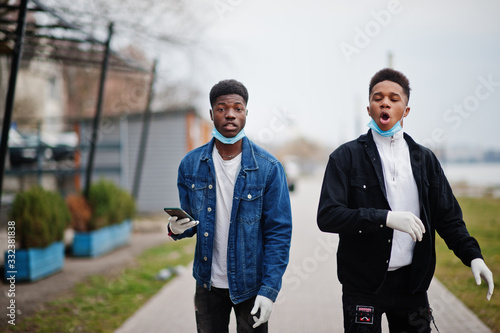 Two african teenagers friends at park wearing medical masks protect from infections and diseases coronavirus virus quarantine.