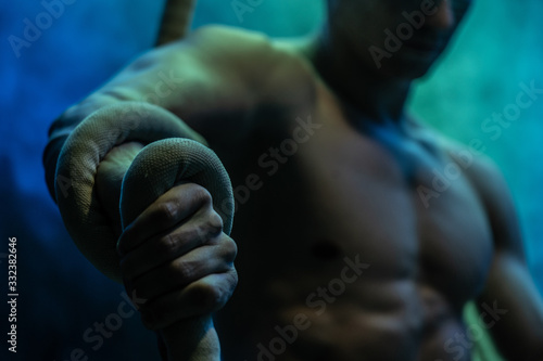 Muscular male circus artist with Cord Lisse on black an smoked background