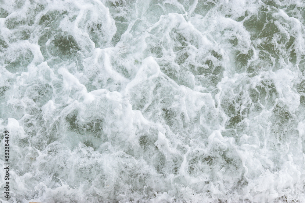 Fototapeta premium Top view texture waves, foaming and splashing in the ocean, sunny day. Beautiful tropical sea in summer season image by aerial view. Abstract sea background. Ocean waves close-up.