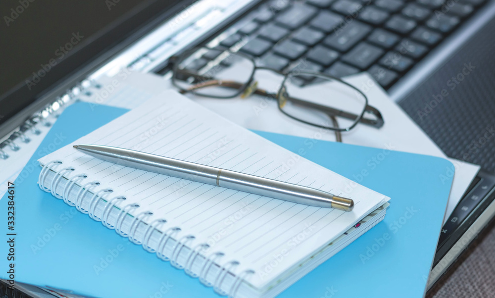 Workplace with laptop, notebook and glasses on a wooden table. Telework. Work from home. Blurred background Workplace with laptop, notebook and glasses on a wooden table. Telework. Work from home. Blurred background